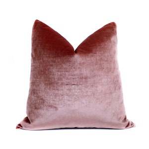 May include: A soft, dusty rose velvet cushion with a simple, rectangular shape.
