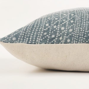 May include: A blue and white patterned throw pillow with a white border. The pillow is made of a soft, textured fabric.