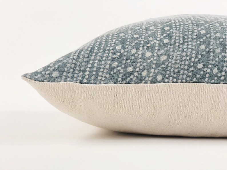 May include: A blue and white patterned throw pillow with a white border. The pillow is made of a soft, textured fabric.