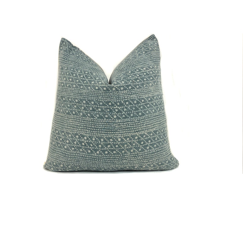 May include: A blue throw pillow with a white geometric pattern. The pillow is made of a soft, textured fabric.