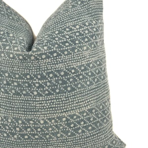 May include: A blue and white patterned throw pillow with a geometric design. The pillow is made of a soft, textured fabric.