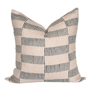 May include: A beige throw pillow with a black and white geometric pattern. The pattern is made up of horizontal stripes that create a checkered effect.