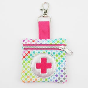 Può includere: Piccola custodia colorata per kit di pronto soccorso con cerniera argentata e un'emblema a croce rosa. La custodia ha un design a fantasia con una clip argentata e un cinturino rosa per un facile fissaggio.