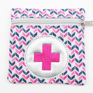 Può includere: Una piccola pochette con cerniera rosa e blu con sfondo bianco e un motivo a chevron. La pochette ha un cerchio argentato con un segno più rosa al centro.
