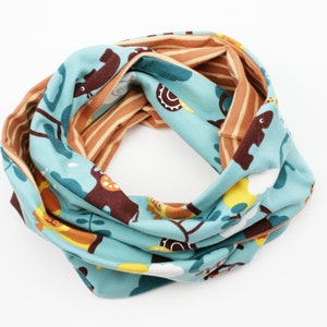 Könnte beinhalten: Ein blauer und brauner, reversibler Infinity-Schal mit einem Waldtier-Druck. Der Schal zeigt verschiedene Tiere, darunter Eichhörnchen, Hirsche und Vögel.