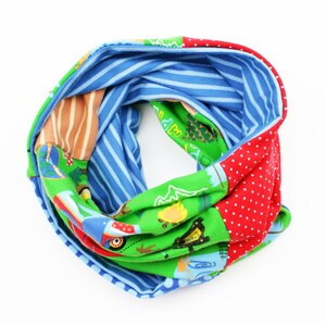 Könnte beinhalten: Ein farbenfroher Stoff-Halswärmer mit einem blauen Streifenmuster, einem grünen Muster mit Camping-Motiv, einem roten Muster mit weißen Punkten und einem braunen und orangefarbenen Streifenmuster.