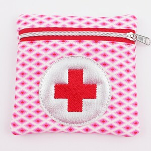 Può includere: Piccola pochette quadrata per kit di pronto soccorso con cerniera rossa e tiretto argentato. La pochette presenta un motivo a rombi rosa e bianchi e una toppa circolare con croce rossa su sfondo argentato.