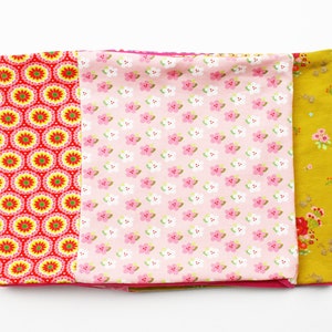 May include: A set of three fabric scraps with different patterns. The first scrap is red with yellow and white circles, the second is pink with white flowers, and the third is yellow with small brown flowers.