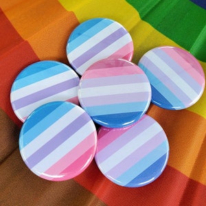 May include: Six round, colourful buttons with a striped pattern. The buttons are arranged in a semi-circle on a rainbow background.