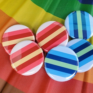 May include: Six colourful striped buttons with a red, white and blue colour scheme. The buttons are arranged in a circle on a rainbow-coloured background.