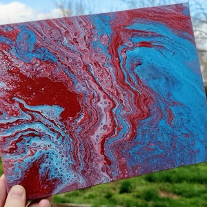 Puede incluir: Pintura abstracta sobre lienzo con pintura roja, azul y blanca en espiral. Los colores se mezclan para crear un diseño único y llamativo.