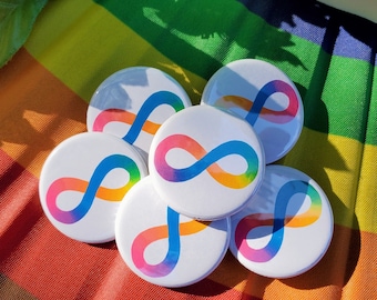 May include: Six round rainbow-colored buttons with an infinity symbol in the center. The buttons are arranged in a circle on a rainbow-colored fabric background.