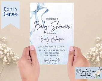 May include: A baby shower invitation with a watercolor blue ribbon design. The invitation includes the text "Join us for a Baby Shower in honor of Emily Johnson" and event details. The invitation is held by two hands.
