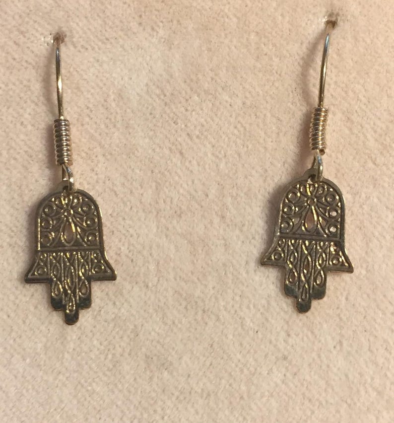 14 Karat Yellow Gold Hamsa Earrings with French Wires Hamsa is .625 in tall with Ear Wires 1.125 tall Shipped USPS Mail 
 The hamsa, or hamsa hand, is a talisman from the ancient Middle East. In its most common form, the amulet is shaped like a hand with three extended fingers in the middle and a curved thumb or pinky finger on either side. It is thought to protect against the “evil eye." It is most often displayed on necklaces or bracelets, and earrings
