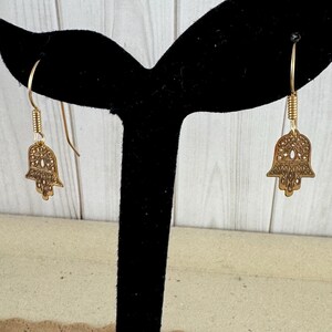 14 Karat Yellow Gold Hamsa Earrings with French Wires Hamsa is .625 in tall with Ear Wires 1.125 tall Shipped USPS Mail 
 The hamsa, or hamsa hand, is a talisman from the ancient Middle East. In its most common form, the amulet is shaped like a hand with three extended fingers in the middle and a curved thumb or pinky finger on either side. It is thought to protect against the “evil eye." It is most often displayed on necklaces or bracelets, and earrings