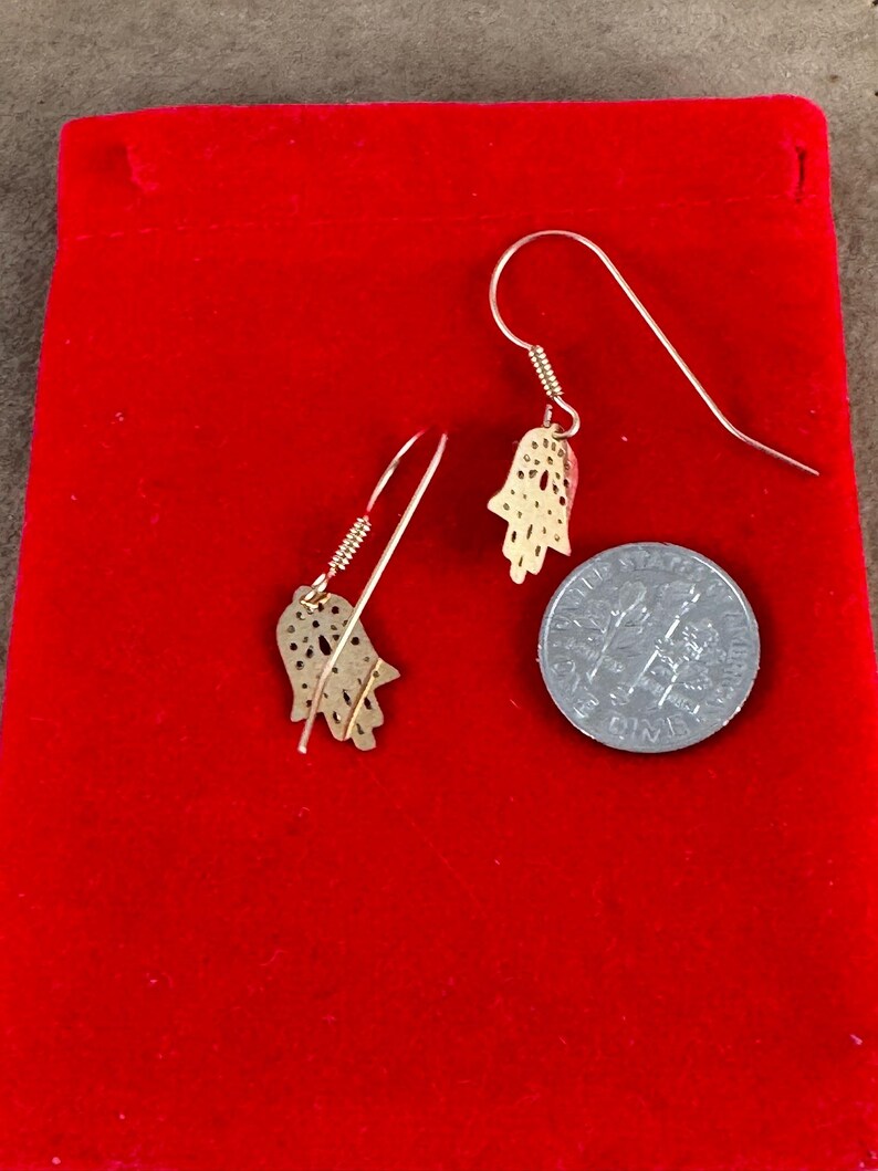 14 Karat Yellow Gold Hamsa Earrings with French Wires Hamsa is .625 in tall with Ear Wires 1.125 tall Shipped USPS Mail 
 The hamsa, or hamsa hand, is a talisman from the ancient Middle East. In its most common form, the amulet is shaped like a hand with three extended fingers in the middle and a curved thumb or pinky finger on either side. It is thought to protect against the “evil eye." It is most often displayed on necklaces or bracelets, and earrings