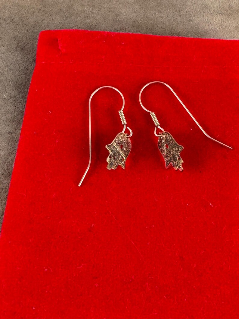 14 Karat Yellow Gold Hamsa Earrings with French Wires Hamsa is .625 in tall with Ear Wires 1.125 tall Shipped USPS Mail 
 The hamsa, or hamsa hand, is a talisman from the ancient Middle East. In its most common form, the amulet is shaped like a hand with three extended fingers in the middle and a curved thumb or pinky finger on either side. It is thought to protect against the “evil eye." It is most often displayed on necklaces or bracelets, and earrings