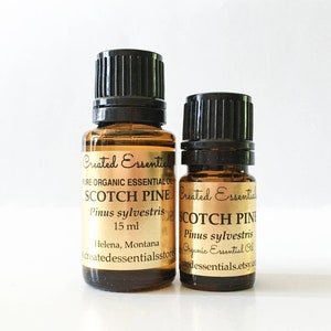 May include: Two amber glass bottles with black caps containing Scotch Pine essential oil. The bottles are labeled with the text "Created Essentials" and "Scotch Pine Pinus sylvestris". The larger bottle is 15 ml and the smaller bottle is 10 ml.