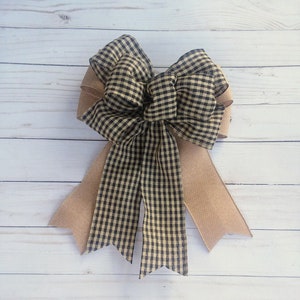 May include: A large black and white gingham bow with a burlap tail. The bow is tied with a double loop and has a rustic, farmhouse style.