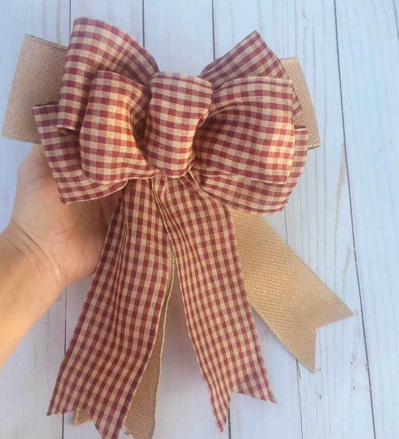 May include: A red and white gingham bow with a burlap tail. The bow is tied in a large, full knot.