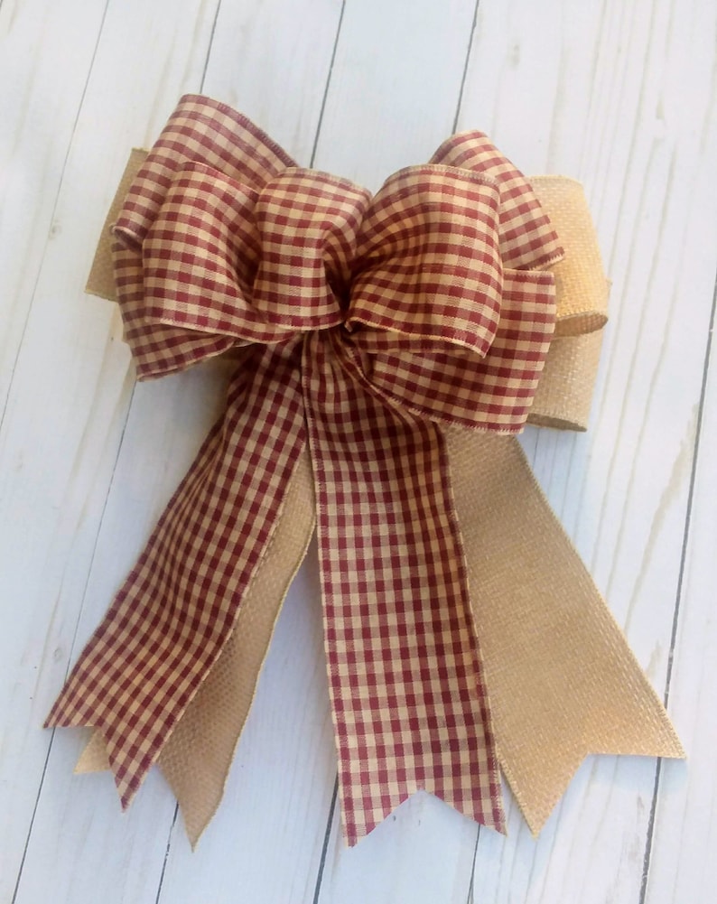 May include: A red and white gingham bow with a burlap bow tail. The bow is tied with a knot in the center and has two tails.