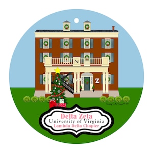May include: A round ornament featuring a brown building with wreaths on the windows and a Christmas tree. The ornament has the text "Delta Zeta University of Virginia Lambda Delta Chapter" in a black and white frame.
