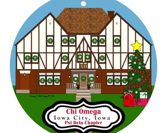 Könnte beinhalten: Ein runder Weihnachtsschmuck mit einem Haus, das für die Feiertage geschmückt ist. Das Haus ist braun und weiß mit Kränzen in den Fenstern und einem Weihnachtsbaum. Der Schmuck trägt den Text "Chi Omega Iowa City, Iowa Psi Beta Chapter."