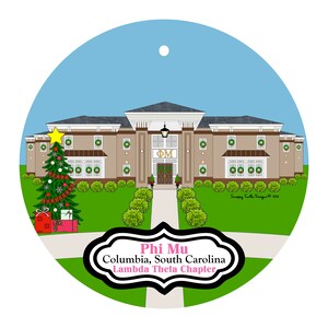 May include: A round Christmas ornament featuring a building with the Greek letters "ΦΜ" above the entrance. A decorated Christmas tree and wrapped gifts are on the left. The text reads "Phi Mu Columbia, South Carolina Lambda Theta Chapter."