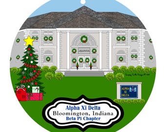 May include: A round Christmas ornament featuring a white building with wreaths and a Christmas tree. The ornament has the text "Alpha Xi Delta Bloomington, Indiana Beta Pi Chapter" and "ALPHA XI DELTA" on a sign.