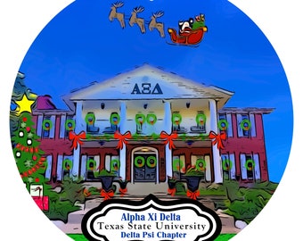 May include: A round Christmas ornament featuring a building decorated with wreaths and red bows. Santa Claus in a sleigh pulled by reindeer flies above the building. The ornament has the text "Alpha Xi Delta Texas State University Delta Psi Chapter."