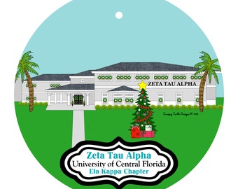 Könnte beinhalten: Ein runder Weihnachtsschmuck mit einem Gebäude mit dem Text "Zeta Tau Alpha" und "University of Central Florida Eta Kappa Chapter". Ein geschmückter Weihnachtsbaum und Palmen sind ebenfalls zu sehen. Der Schmuck hat einen hellblauen Himmel und einen grünen Gras-Hintergrund.