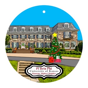 May include: A round Christmas ornament featuring a detailed illustration of a building with a Christmas tree and presents. The ornament has the text "Pi Beta Phi University of Kansas Kansas Alpha Chapter". The background is blue.
