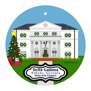May include: A round ornament featuring a white house with columns, green wreaths on windows, and a Christmas tree with a yellow star. Text reads Delta Gamma, Athens, Georgia, Delta Iota Chapter, and Merry Christmas on the tree ribbon.