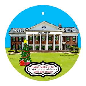 May include: A round Christmas ornament featuring a building with the text "KAPPA ALPHA" above the entrance. A decorated Christmas tree and gifts are in front of the building. The text "Kappa Alpha Order, University of Alabama, Alpha Beta Chapter" is also present.