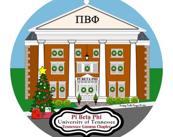 May include: A round Christmas ornament featuring a brown building with white columns and the Greek letters ПВФ. The building has wreaths on the windows and a Christmas tree. The text "Pi Beta Phi University of Tennessee Tennessee Gamma Chapter" is also present.