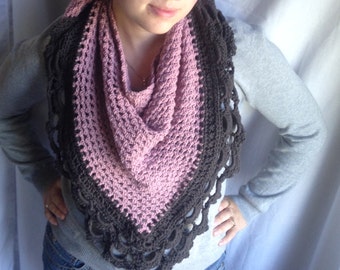 May include: A pink and brown crocheted shawl with a lacy border. The shawl is worn by a person, but the person's face is not visible.