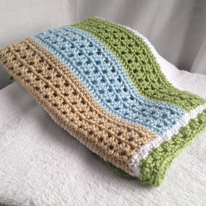 May include: A crocheted baby blanket with stripes of tan, light blue, white, and green.