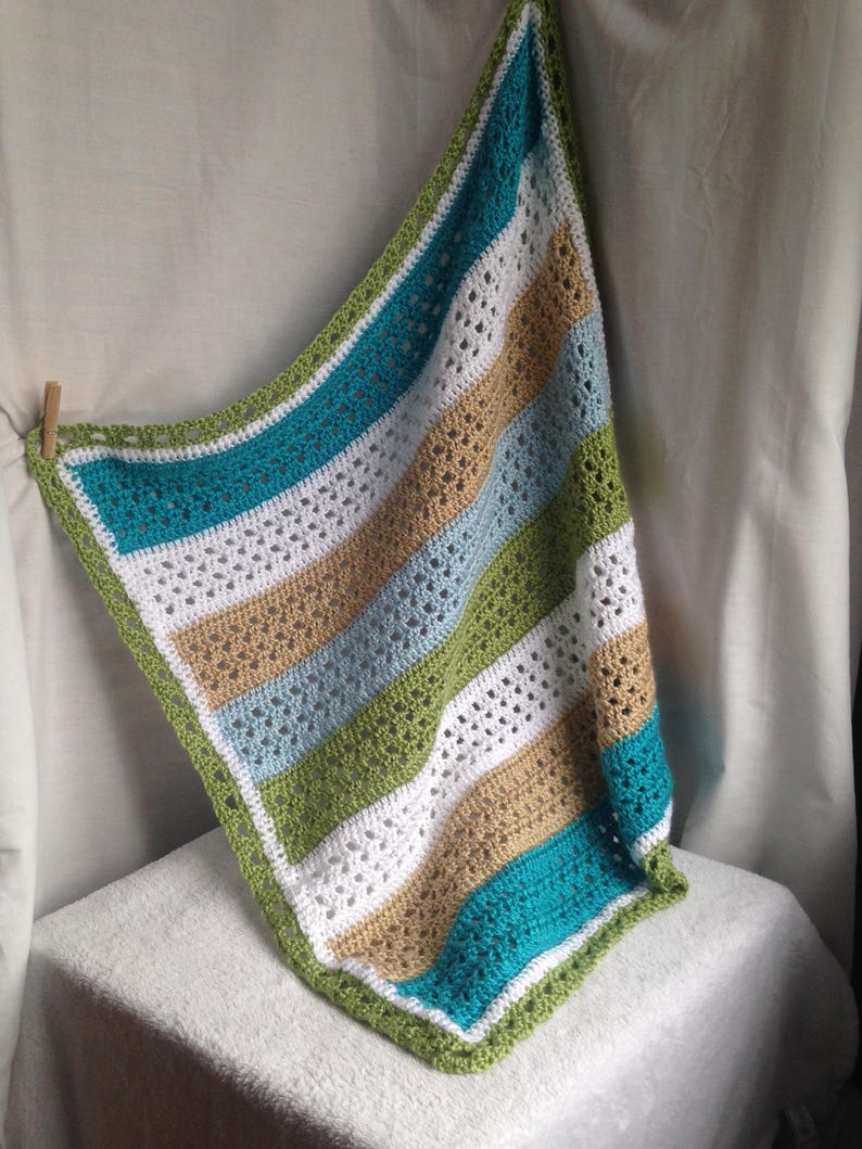 May include: A crocheted baby blanket with stripes of white, teal, light blue, green, and tan.