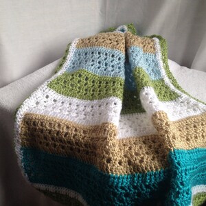 May include: A crocheted baby blanket with stripes of white, tan, green, blue, and teal.