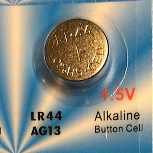 May include: A package of ten LR44 AG13 1.5V alkaline button cell batteries. Each gold-colored battery is in a clear plastic blister pack. The text "1.5V Alkaline Button Cell" is printed on the packaging.