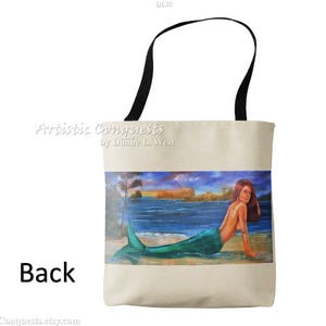 Pode incluir: Uma bolsa tote bege com al&ccedil;as pretas. A bolsa apresenta uma pintura colorida de uma sereia com cabelo verde e cauda, nadando em um corpo de &aacute;gua azul. O texto "Artistic Conquests by Dianne L. West" est&aacute; impresso na bolsa.