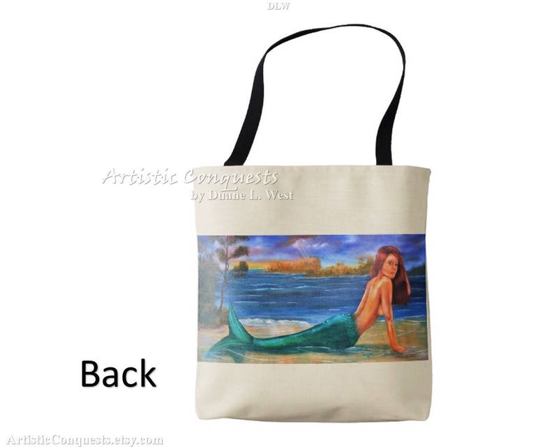 Pode incluir: Uma bolsa tote bege com al&ccedil;as pretas. A bolsa apresenta uma pintura colorida de uma sereia com cabelo verde e cauda, nadando em um corpo de &aacute;gua azul. O texto "Artistic Conquests by Dianne L. West" est&aacute; impresso na bolsa.