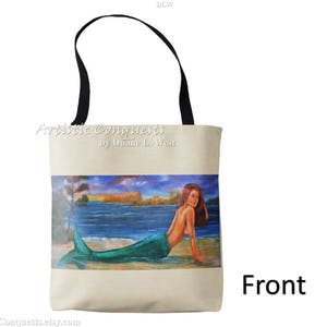 Pode incluir: Uma bolsa tote bege com al&ccedil;as pretas e uma imagem impressa de uma sereia com cabelo comprido vermelho, uma cauda verde e um fundo azul. O texto "Artistic Conquests by Dianne L. West" est&aacute; impresso na bolsa. A palavra "Front" est&aacute; impressa abaixo da imagem.