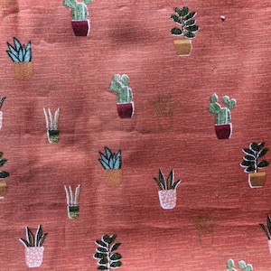 May include: A red fabric with a repeating pattern of potted plants. The plants are green and brown and are in various shapes and sizes. The fabric has a subtle texture.