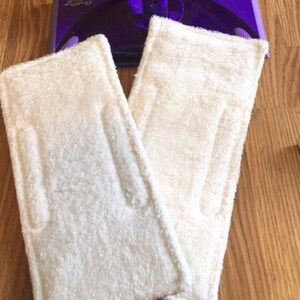 May include: Two white microfiber mop pads for a Swiffer WetJet mop. The pads are made of a soft, absorbent material and are designed to clean and polish floors.