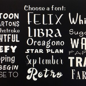 K&ouml;nnte beinhalten: Eine schwarze Tafel mit dem Text "W&auml;hlen Sie eine Schriftart:" in wei&szlig;. Unter dem Text stehen verschiedene W&ouml;rter in verschiedenen Schriftarten, darunter "Cartoon", "Felix", "Whimsy", "Libra", "Sugar is", "Frightful", "Oreagono", "Wave", "Beefy", "Star Plan", "Farfel", "Ciscoping", "September", "Trade", "Edo Begin", "Retro" und "Farmer".