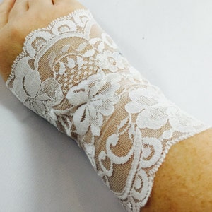 May include: White lace wrist cuffs with a floral pattern.