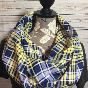 May include: A yellow and navy blue plaid infinity scarf. The scarf is made of a soft, comfortable fabric and is perfect for keeping warm in the winter.