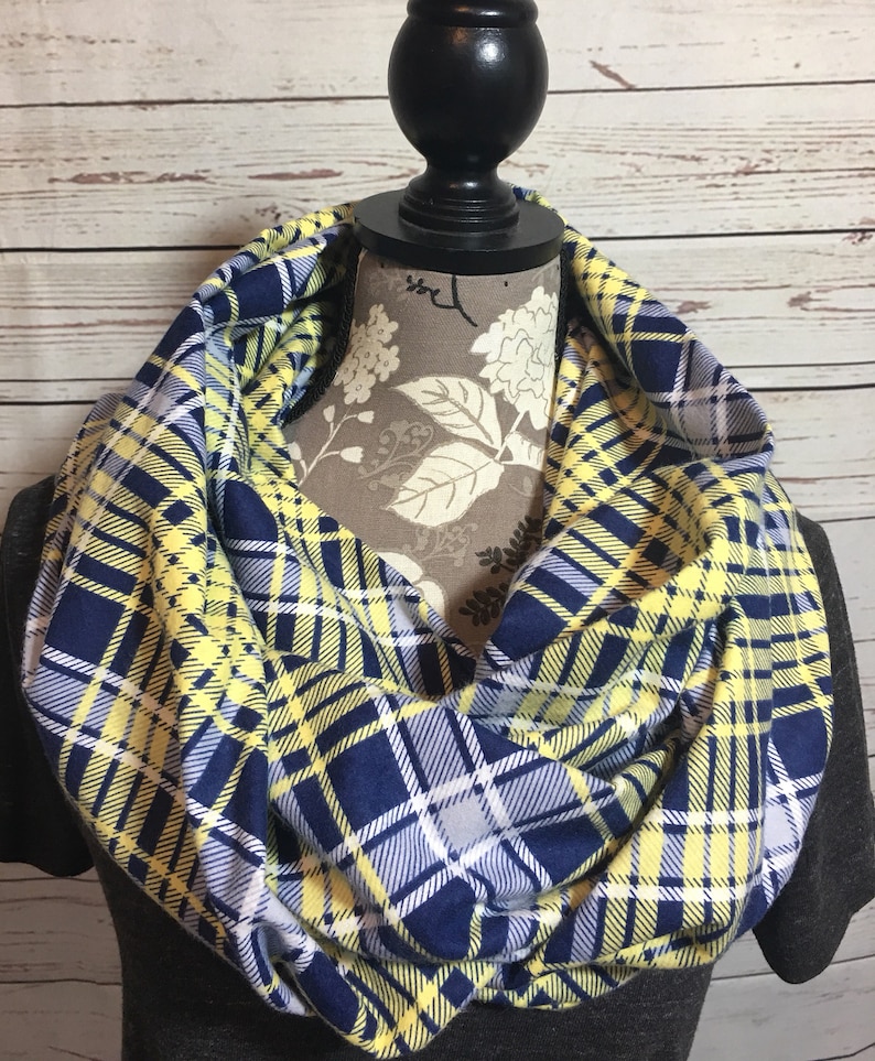 May include: A yellow and navy blue plaid infinity scarf. The scarf is made of a soft, comfortable fabric and is perfect for keeping warm in the winter.