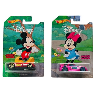 May include: Two Hot Wheels Disney character cars, one red with Mickey Mouse and the other pink with Minnie Mouse. The cars are on their packaging with the characters on the background.